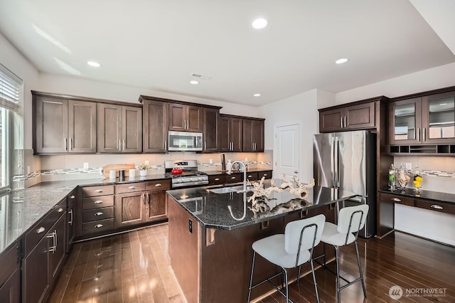 3613 198th Pl SE, Bothell, WA 98012 - kitchen featuring appliances with stainless steel finishes, dark wood finished floors, dark stone counters, a breakfast bar area, and dark brown cabinets
