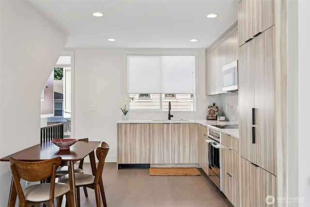 4303 Dayton Ave N Unit E, Seattle, WA 98103 - kitchen featuring high end range, modern cabinets, light countertops, light brown cabinetry, and light wood-style flooring