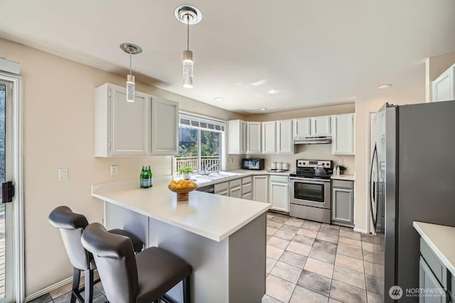 34427 10th Ave SW, Federal Way, WA 98023 - kitchen featuring appliances with stainless steel finishes, a peninsula, under cabinet range hood, light countertops, and a kitchen bar