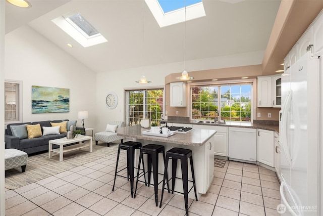8612 218th St SW, Edmonds, WA 98026 - kitchen featuring white appliances, a skylight, light tile patterned floors, high vaulted ceiling, and a breakfast bar