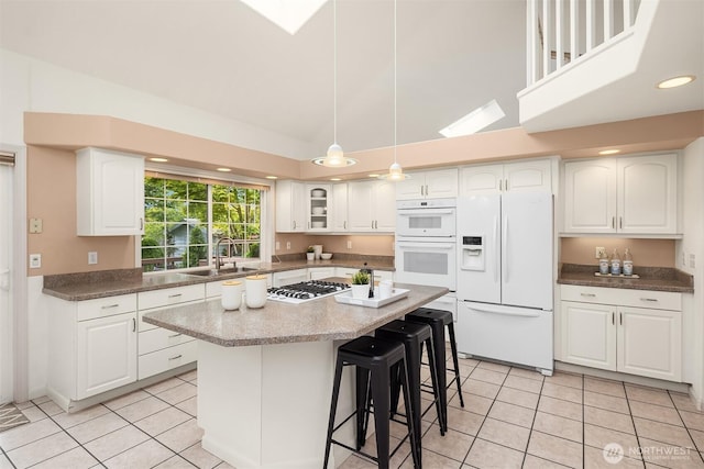 8612 218th St SW, Edmonds, WA 98026 - kitchen with white appliances, light tile patterned floors, white cabinetry, a breakfast bar area, and recessed lighting