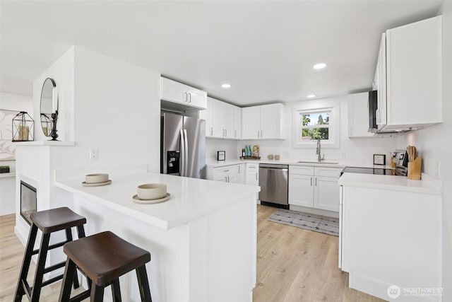 12448 Occidental Ave S, Seattle, WA 98168 - kitchen with stainless steel appliances, a peninsula, light wood-type flooring, a breakfast bar area, and light countertops