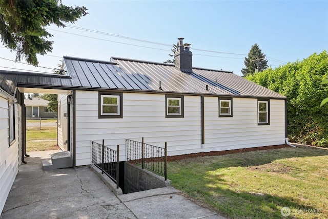 12448 Occidental Ave S, Seattle, WA 98168 - view of home's exterior featuring a standing seam roof, a chimney, a yard, a metal roof, and a patio