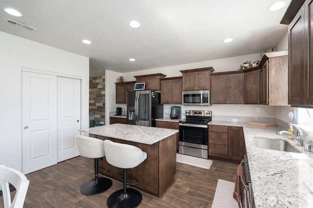 4211 W Heaverlo Dr, Moses Lake, WA 98837 - kitchen with stainless steel appliances, a center island, a kitchen bar, dark wood finished floors, and light stone countertops