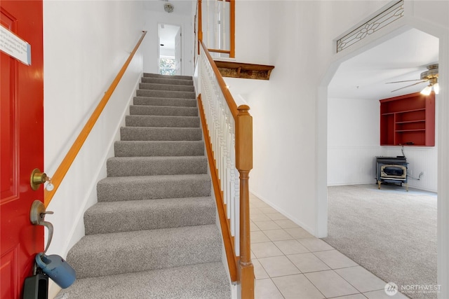 19517 Whiteman Cove Rd SW, Longbranch, WA 98351 - staircase featuring carpet floors, ceiling fan, tile patterned floors, a wood stove, and arched walkways