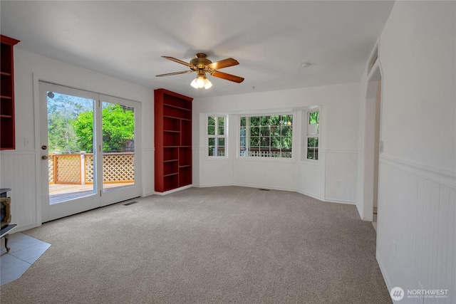 19517 Whiteman Cove Rd SW, Longbranch, WA 98351 - empty room featuring ceiling fan, a wainscoted wall, carpet, a wood stove, and built in features