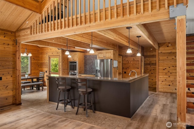 7717 252nd Ave NE, Redmond, WA 98053 - kitchen with appliances with stainless steel finishes, wood walls, light wood-type flooring, a wood ceiling with exposed beams, and a kitchen bar
