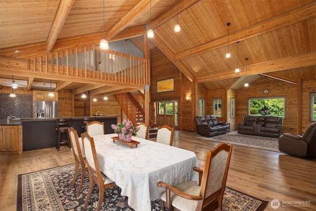 7717 252nd Ave NE, Redmond, WA 98053 - dining space with wood walls, a wood ceiling with exposed beams, high vaulted ceiling, stairs, and light wood-style flooring