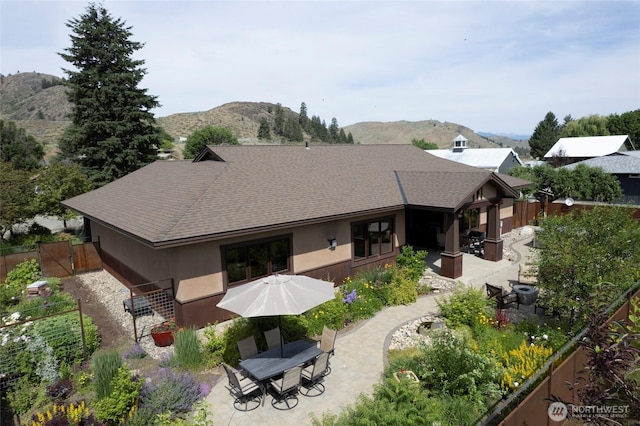 512 May St, Twisp, WA 98856 - rear view of house with a patio area, roof with shingles, a mountain view, outdoor dining area, and stucco siding