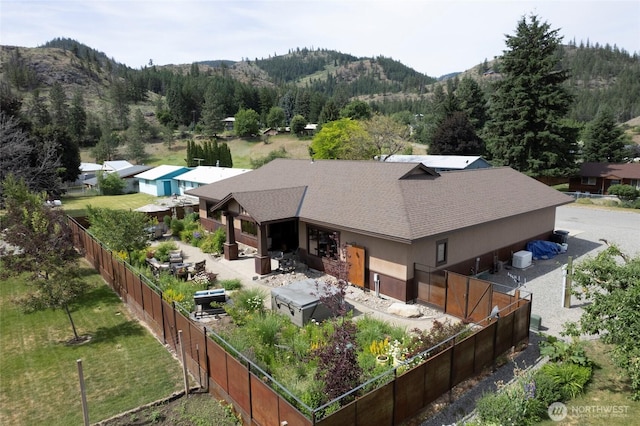 512 May St, Twisp, WA 98856 - rear view of house with a mountain view, roof with shingles, a fenced backyard, stucco siding, and a forest view