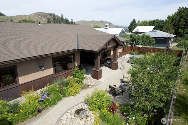 512 May St, Twisp, WA 98856 - back of house with a shingled roof, a patio area, a mountain view, and stucco siding