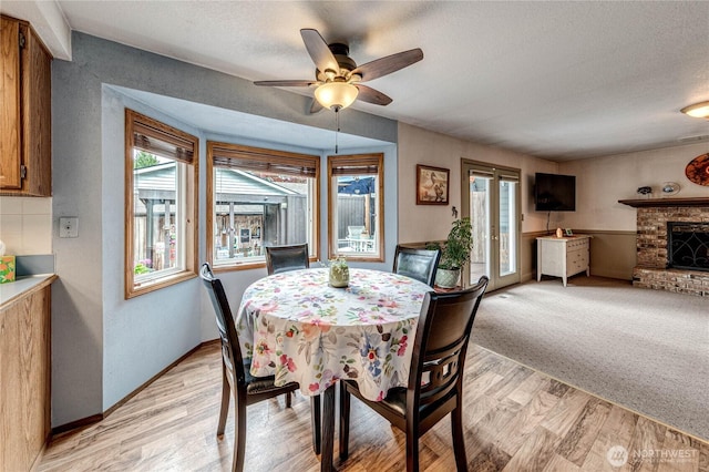 1722 172nd St SE, Bothell, WA 98012 - dining area featuring light wood-type flooring, ceiling fan, a fireplace, a textured ceiling, and french doors
