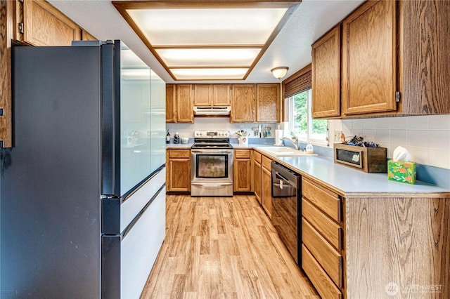 1722 172nd St SE, Bothell, WA 98012 - kitchen with stainless steel appliances, light wood-type flooring, brown cabinetry, light countertops, and under cabinet range hood