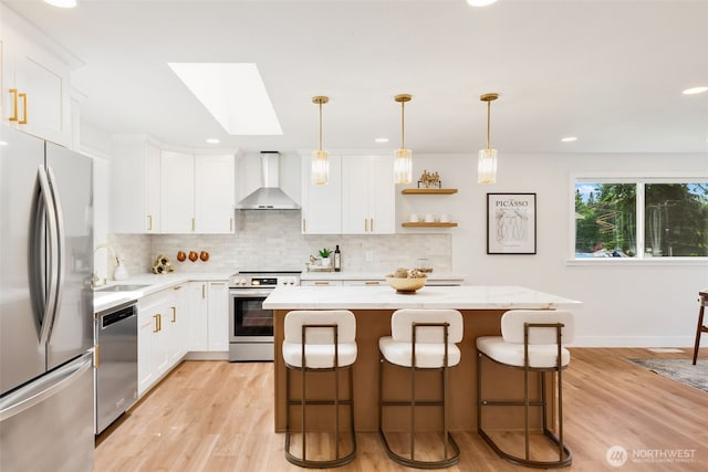 331 137th St SW, Everett, WA 98208 - kitchen featuring appliances with stainless steel finishes, wall chimney exhaust hood, a skylight, a center island, and backsplash