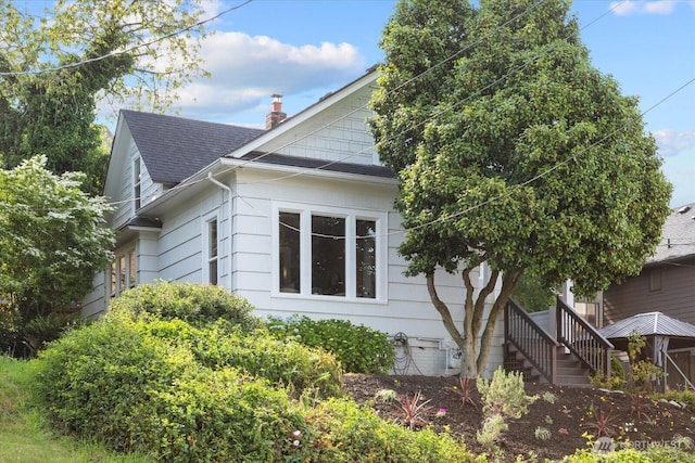 3443 21st Ave W, Seattle, WA 98199 - view of property exterior with a shingled roof, stairs, and a chimney