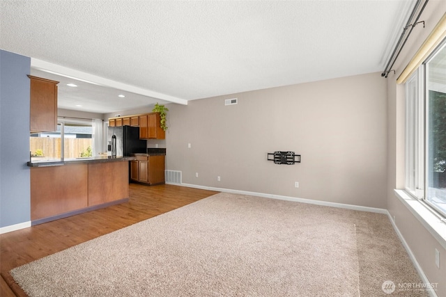 19436 SE 266th St, Covington, WA 98042 - kitchen with black fridge, dark countertops, a peninsula, brown cabinetry, and recessed lighting