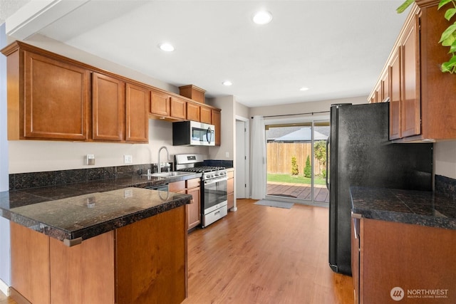19436 SE 266th St, Covington, WA 98042 - kitchen with stainless steel appliances, tile countertops, light wood-style flooring, a peninsula, and brown cabinets
