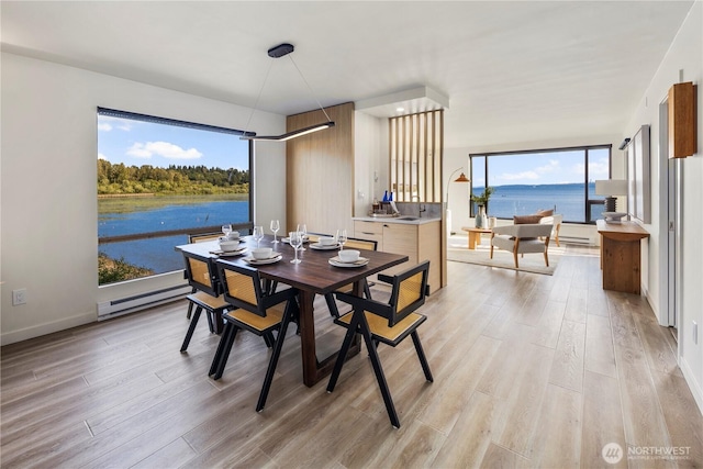 9717 NE Juanita Dr Unit 301A, Kirkland, WA 98034 - dining area featuring a baseboard heating unit, light wood-style flooring, and a water view