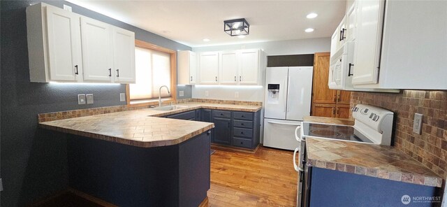 5903 187th Ave SW, Rochester, WA 98579 - kitchen with white appliances, a peninsula, tasteful backsplash, light wood finished floors, and white cabinetry