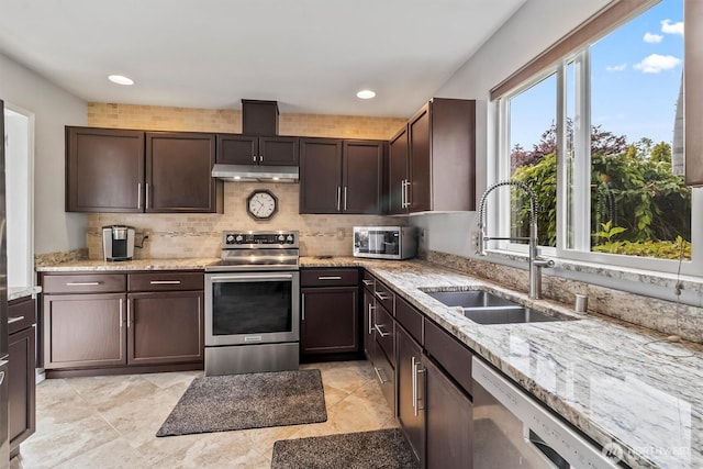 1606 94th Ave NE, Lake Stevens, WA 98258 - kitchen featuring appliances with stainless steel finishes, light stone counters, dark brown cabinets, decorative backsplash, and under cabinet range hood