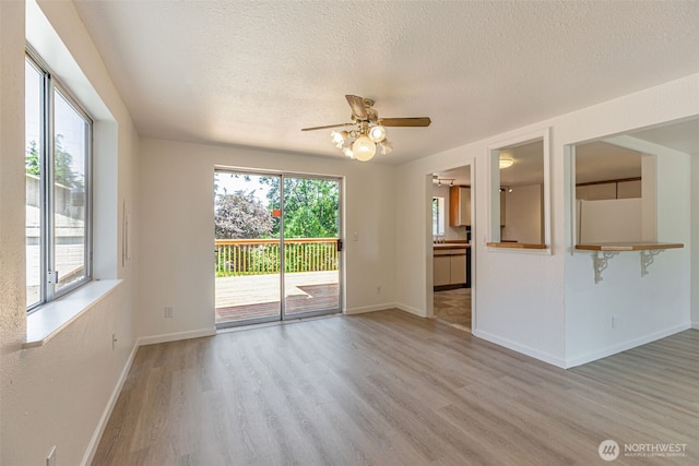 12124 SE 161st St, Renton, WA 98058 - empty room with light wood finished floors, plenty of natural light, a textured ceiling, and a ceiling fan