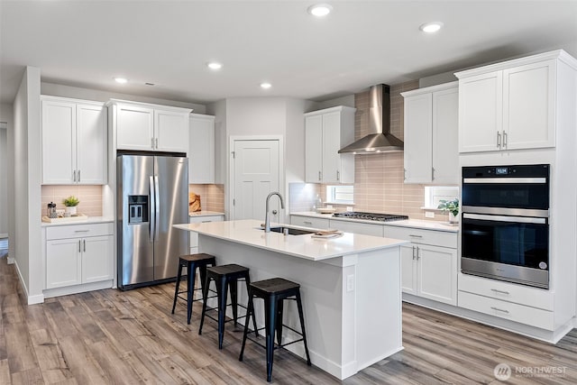 18231 132nd Ave E, Puyallup, WA 98374 - kitchen with appliances with stainless steel finishes, wall chimney exhaust hood, light wood finished floors, decorative backsplash, and recessed lighting