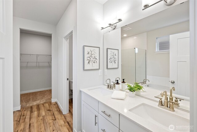 18231 132nd Ave E, Puyallup, WA 98374 - full bathroom featuring wood finished floors, tiled shower, double vanity, a walk in closet, and a garden tub