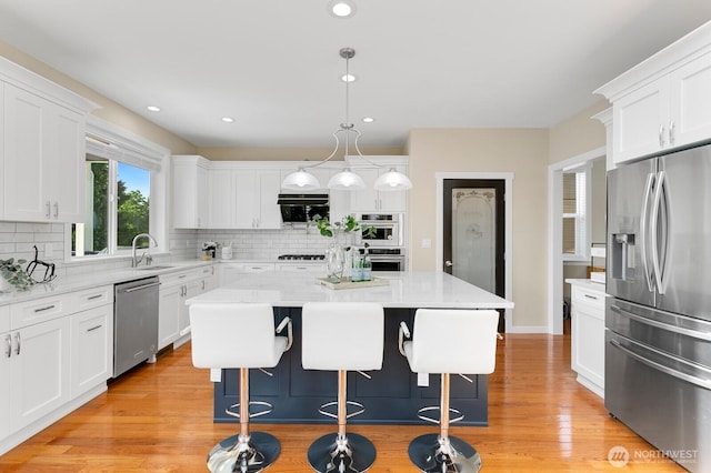 8441 8th Ave SW, Seattle, WA 98106 - kitchen with appliances with stainless steel finishes, a kitchen bar, decorative backsplash, white cabinets, and a center island