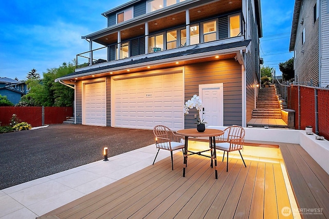 8441 8th Ave SW, Seattle, WA 98106 - rear view of house with an attached garage, stairs, a balcony, asphalt driveway, and outdoor dining area