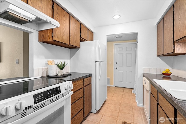3100 Bill Mcdonald Pkwy Unit E101, Bellingham, WA 98225 - kitchen featuring white appliances, ventilation hood, brown cabinetry, light tile patterned flooring, and dark countertops