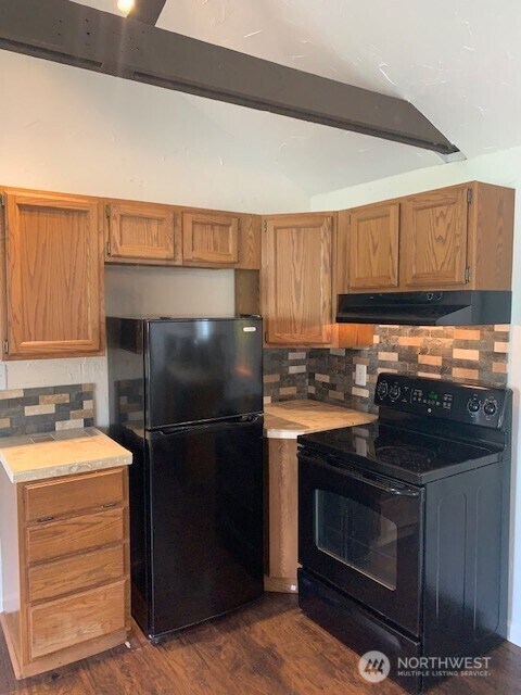 9928 Yakima Ave S, Tacoma, WA 98444 - kitchen featuring black appliances, under cabinet range hood, beamed ceiling, light countertops, and tasteful backsplash