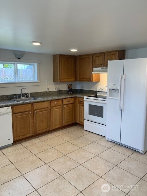 9928 Yakima Ave S, Tacoma, WA 98444 - kitchen featuring white appliances, under cabinet range hood, dark countertops, brown cabinetry, and recessed lighting