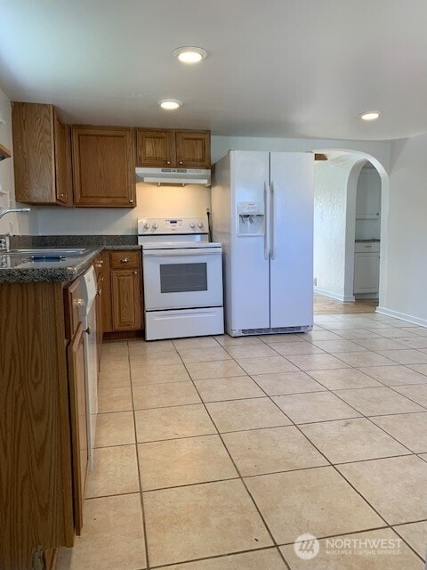9928 Yakima Ave S, Tacoma, WA 98444 - kitchen featuring white appliances, under cabinet range hood, light tile patterned floors, arched walkways, and recessed lighting