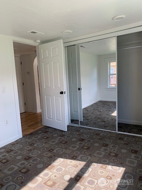 9928 Yakima Ave S, Tacoma, WA 98444 - unfurnished bedroom with a closet, arched walkways, and dark floors
