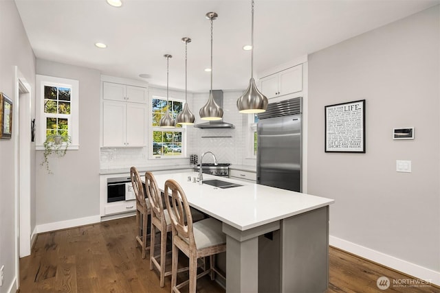 901 W Mcgraw St Unit 6, Seattle, WA 98119 - kitchen with stainless steel built in refrigerator, decorative backsplash, wall chimney range hood, light countertops, and white cabinetry