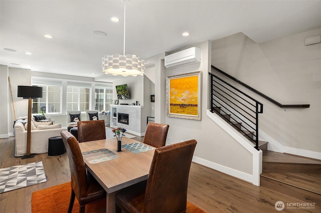 901 W Mcgraw St Unit 6, Seattle, WA 98119 - dining space featuring a wall mounted air conditioner, wood finished floors, a glass covered fireplace, recessed lighting, and stairs