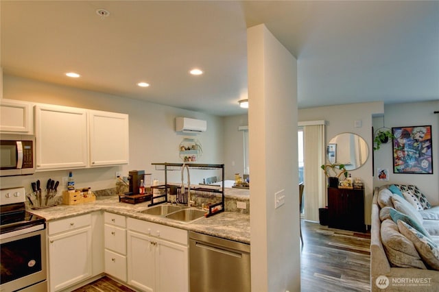 1651SW Mulberry St Unit E304, Oak Harbor, WA 98277 - kitchen featuring appliances with stainless steel finishes, an AC wall unit, open floor plan, dark wood finished floors, and white cabinets