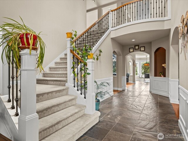 2135 204th Pl NE, Sammamish, WA 98074 - foyer with a high ceiling, stone tile floors, arched walkways, stairway, and a wainscoted wall