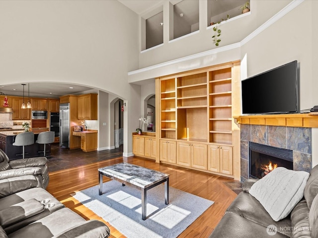 2135 204th Pl NE, Sammamish, WA 98074 - living area with arched walkways, a towering ceiling, a fireplace, and dark wood-type flooring