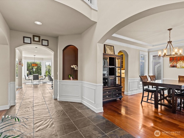 2135 204th Pl NE, Sammamish, WA 98074 - dining room featuring a chandelier, a decorative wall, wainscoting, crown molding, and arched walkways