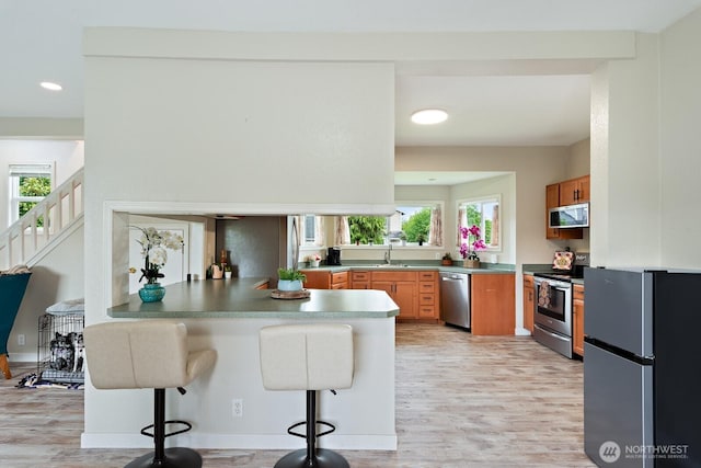 27902 69th Ave NW, Stanwood, WA 98292 - kitchen featuring stainless steel appliances, light wood-style floors, a peninsula, recessed lighting, and a kitchen breakfast bar