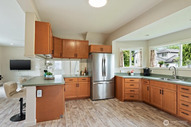 27902 69th Ave NW, Stanwood, WA 98292 - kitchen featuring freestanding refrigerator, light wood-type flooring, a breakfast bar area, a peninsula, and brown cabinets