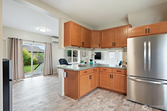 27902 69th Ave NW, Stanwood, WA 98292 - kitchen featuring freestanding refrigerator, an AC wall unit, a peninsula, and light wood-style floors