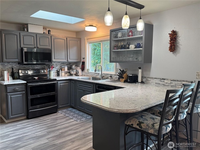 4313 131st St SE, Everett, WA 98208 - kitchen featuring double oven range, stainless steel microwave, gray cabinetry, a skylight, and a peninsula
