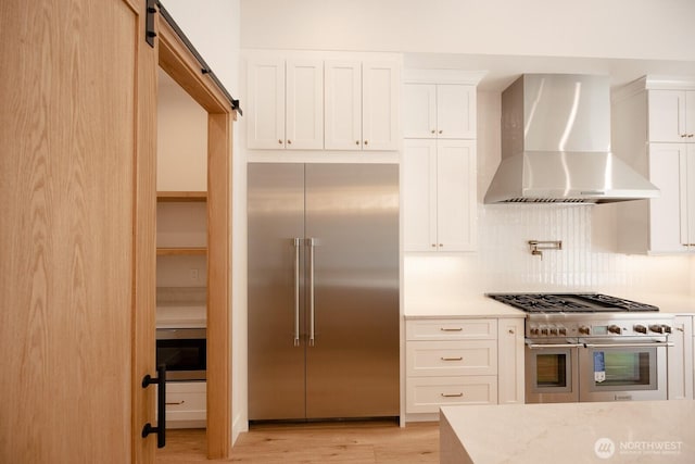 24018 Dolphin Ln, Mount Vernon, WA 98274 - kitchen with wall chimney range hood, premium appliances, backsplash, light wood finished floors, and white cabinets
