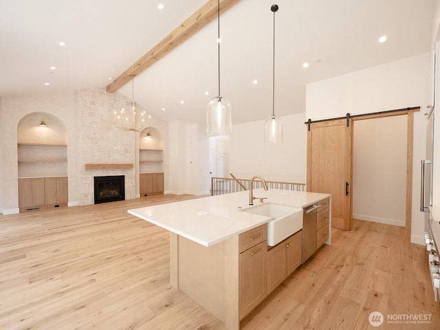 24018 Dolphin Ln, Mount Vernon, WA 98274 - kitchen with a barn door, light wood-style flooring, a center island with sink, stainless steel dishwasher, and a fireplace