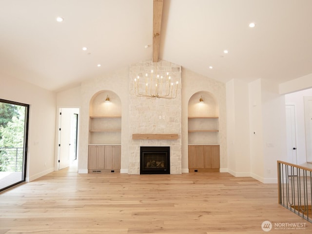 24018 Dolphin Ln, Mount Vernon, WA 98274 - unfurnished living room featuring built in shelves, light wood-style flooring, beam ceiling, a chandelier, and a stone fireplace