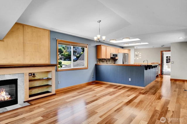 4138 21st Ave SW, Seattle, WA 98106 - kitchen with stainless steel appliances, light wood-style flooring, a chandelier, a peninsula, and light brown cabinets