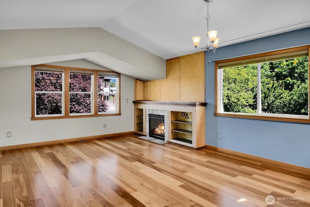 4138 21st Ave SW, Seattle, WA 98106 - unfurnished living room featuring plenty of natural light, light wood finished floors, a tile fireplace, lofted ceiling, and a chandelier