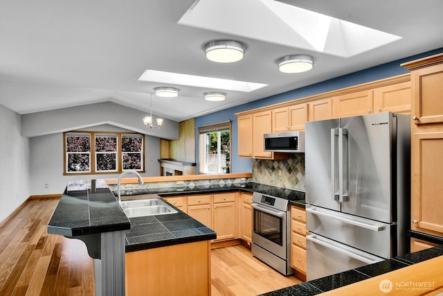 4138 21st Ave SW, Seattle, WA 98106 - kitchen with stainless steel appliances, a skylight, tile counters, light wood finished floors, and lofted ceiling